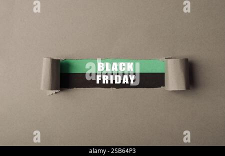 Un pezzo di carta strappato con le parole del Black Friday scritte sopra. La carta è strappata a metà, con le parole a sinistra e la parola venerdì a r Foto Stock