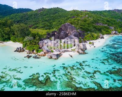 Vista aerea di Anse Source D'Argent a la Digue, Seychelles, con lussureggianti foreste verdi, iconiche formazioni rocciose di granito, spiaggia di sabbia bianca e Clear Foto Stock