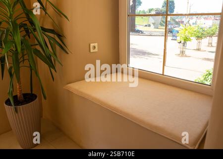 Un intimo caffè dall'atmosfera calda e familiare, caratterizzato da un soffice davanzale con ampia finestra inondata di luce naturale, perfetto per il relax e il comfort. Foto Stock