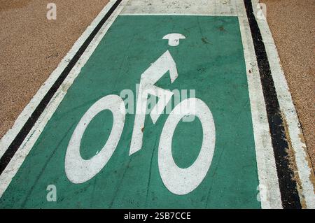 Strada urbana con una pista ciclabile designata, contrassegnata da un simbolo di bicicletta bianco su una superficie verniciata di verde, che mette in evidenza i trasporti ecologici nel ci Foto Stock