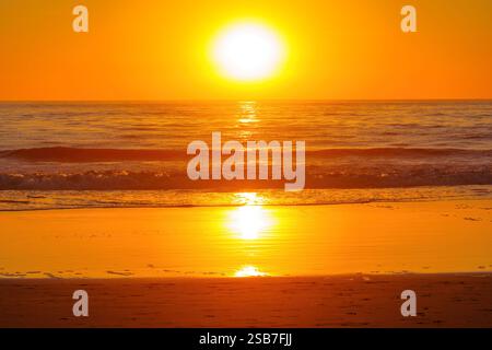 Il tramonto dorato mozzafiato proietta vivaci sfumature sulle onde dell'oceano a Venice Beach, creando un'atmosfera tranquilla. Foto Stock