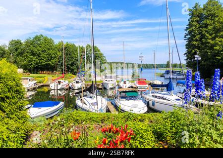 Barche a vela ormeggiate nel piccolo porticciolo di Giano pieno di fiori colorati vicino alla città di Ruciane Nida, al distretto dei laghi di Mazury, Polonia Foto Stock