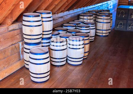 Una fila di barili è impilata l'una sull'altra. Le botti sono di legno e blu. I barili sono impilati in modo che siano tutti rivolti allo stesso modo Foto Stock