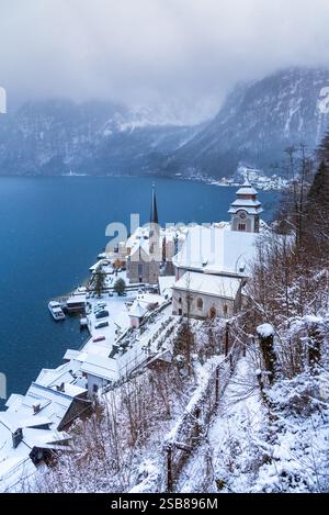 Hallstatt, Austria. Villaggio innevato nelle Alpi austriache e sul lago Hallstattersee montagne torreggianti avvolte da una bufera di neve invernale. Foto Stock