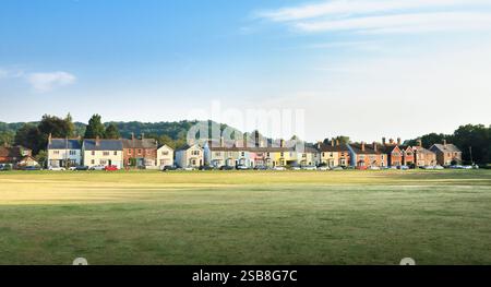 Una fila di affascinanti e colorate case a schiera dipinte in colori pastello che si affacciano sul verde ai margini di Reigate Heath nel Surrey, Inghilterra, Regno Unito Foto Stock