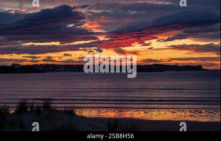 Tramonto sulla spiaggia di Loredo nel comune di Somo nella provincia di Santander, con vista sull'isola costiera e grandi nuvole Foto Stock