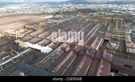 Vista aerea ad alto angolo di un grande stabilimento siderurgico di Esch-sur-Alzette, Lussemburgo, con magazzini, sale di produzione, gru, binari ferroviari e infrastrutture industriali. Foto Stock