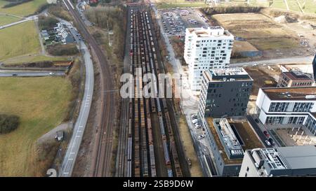 Vista aerea ad alto angolo di Esch-sur-Alzette, Lussemburgo, con uno scalo ferroviario con treni merci parcheggiati, moderni edifici residenziali e commerciali, strade e spazi verdi circostanti. Foto Stock