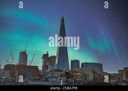 Lo skyline di Londra, caratterizzato dallo Shard, è raffigurato sotto un cielo notturno con la vibrante aurora boreale. Edifici moderni e una nave storica sono importanti Foto Stock
