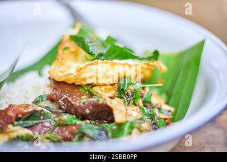 Pad Kra Pao. Frittura in padella di manzo di basilico in stile tailandese con uova fritte. Menu di piatti thailandesi Foto Stock