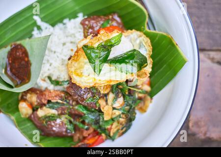 Pad Kra Pao. Frittura in padella di manzo di basilico in stile tailandese con uova fritte. Menu di piatti thailandesi Foto Stock