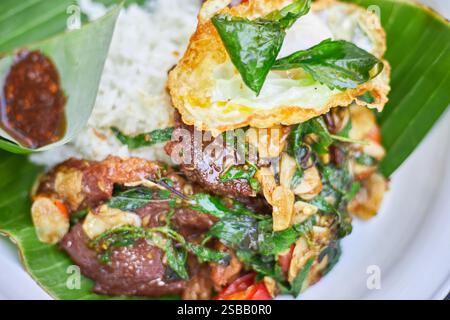 Pad Kra Pao. Frittura in padella di manzo di basilico in stile tailandese con uova fritte. Menu di piatti thailandesi Foto Stock