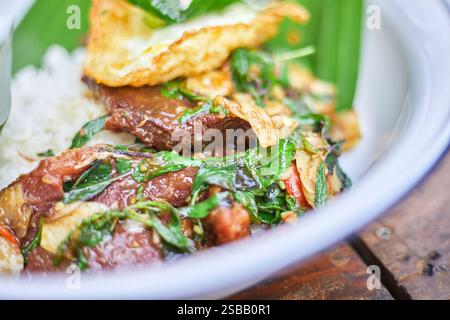 Pad Kra Pao. Frittura in padella di manzo di basilico in stile tailandese con uova fritte. Menu di piatti thailandesi Foto Stock