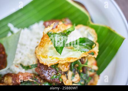 Pad Kra Pao. Frittura in padella di manzo di basilico in stile tailandese con uova fritte. Menu di piatti thailandesi Foto Stock