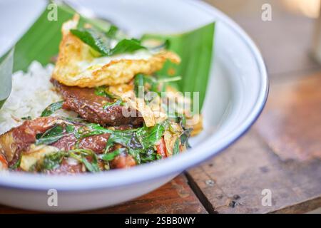 Pad Kra Pao. Frittura in padella di manzo di basilico in stile tailandese con uova fritte. Menu di piatti thailandesi Foto Stock
