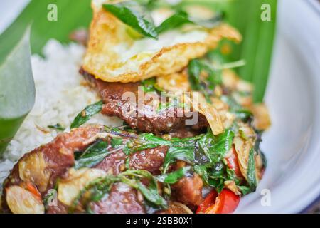 Pad Kra Pao. Frittura in padella di manzo di basilico in stile tailandese con uova fritte. Menu di piatti thailandesi Foto Stock