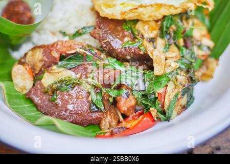 Pad Kra Pao. Frittura in padella di manzo di basilico in stile tailandese con uova fritte. Menu di piatti thailandesi Foto Stock