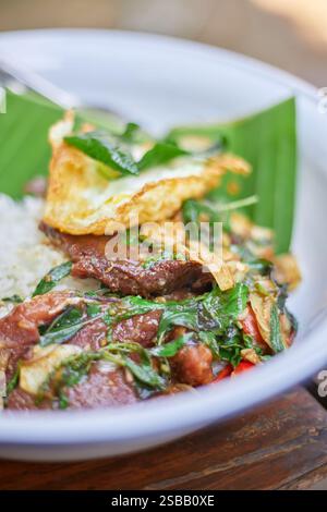 Pad Kra Pao. Frittura in padella di manzo di basilico in stile tailandese con uova fritte. Menu di piatti thailandesi Foto Stock