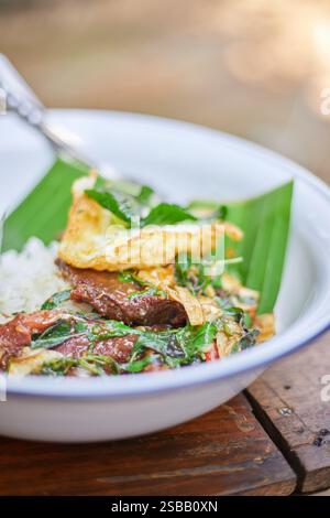 Pad Kra Pao. Frittura in padella di manzo di basilico in stile tailandese con uova fritte. Menu di piatti thailandesi Foto Stock