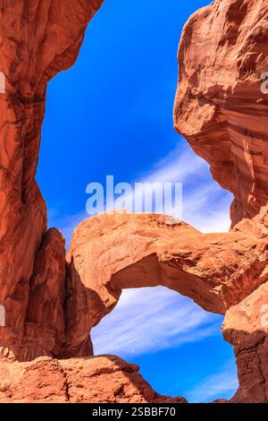 Un grande arco con un cielo blu sopra di esso. L'arco è circondato da rocce e il cielo è limpido e blu Foto Stock