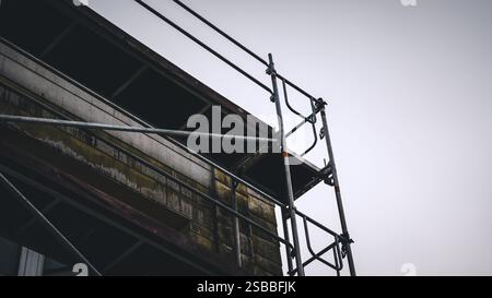 Ponteggio sul posto dell'edificio davanti alla facciata fatiscente sul posto Foto Stock