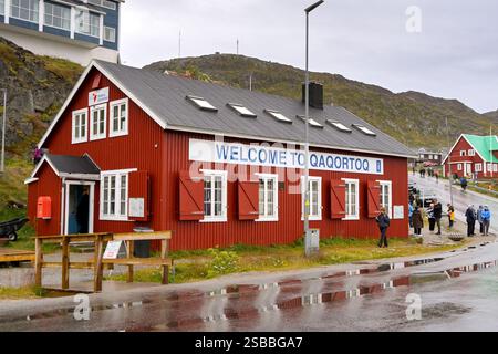 Qaqortoq, Groenlandia - 28 agosto 2024: Persone provenienti da una nave da crociera in visita all'esterno di una nave da regalo souvenir nella remota città di Qaqortoq. Foto Stock
