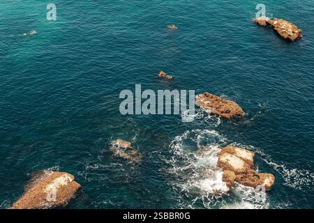 Vista aerea dell'oceano blu profondo con formazioni rocciose sparse e dolci onde. Foto Stock