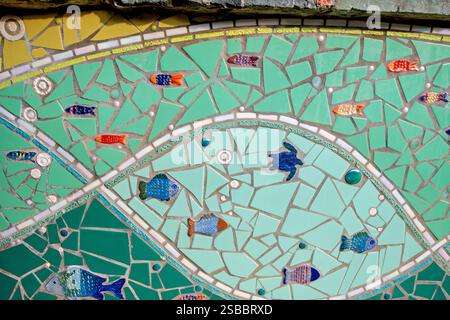 Opera d'arte mosaicata per parco giochi con motivi di pesci e tartarughe Cruz Bay St John USVI | CRUZ BAY, Isole Vergini Americane — Un pannello murale a mosaico su St. John abbina pesci in banco a una tartaruga marina resa con piastrelle di ceramica rotte, incorniciata da bande di tesserae gialle e verdi. Il motivo della tartaruga riflette la presenza di tartarughe marine che depongono le uova sulle spiagge di St. John, parte delle acque protette del Virgin Islands National Park. Mosaici realizzati dalla comunità come questo sono una caratteristica ricorrente degli spazi pubblici nelle Isole Vergini Americane. Foto Stock