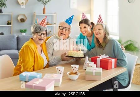Ritratto di Happy Seniors e infermiere che celebrano il compleanno a casa di cura Foto Stock