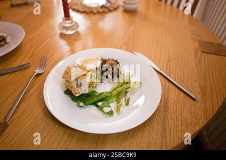 Filetto di spigola servito su un letto di patate novelle, accompagnato da funghi saltati e una varietà di verdure verdi. Foto Stock