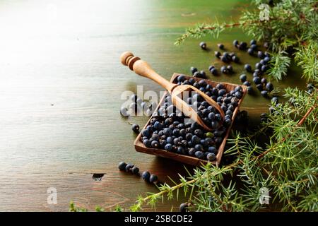 Ciotola di legno con semi di ginepro su un vecchio tavolo di legno. Copia spazio. Foto Stock