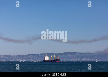 La nave da carico vuota attraversa una scia di gas di scarico lasciando la baia di San Francisco Foto Stock