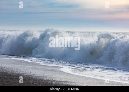 Una grande onda mostruosa si schianta sulla spiaggia in una parete di schiuma d'acqua e spionaggio Foto Stock