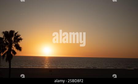 Un tramonto mozzafiato di Venice Beach in California, dove il sole dorato si tuffa sotto l'orizzonte, generando calde sfumature attraverso l'Oceano Pacifico. Foto Stock