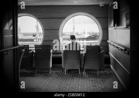 Donna in bianco e nero seduta nella lounge dei traghetti in attesa della partenza da Bari a Dubrovnik, Italia Foto Stock