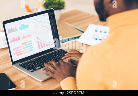Imprenditore nero che analizza il grafico sul notebook sul luogo di lavoro Foto Stock