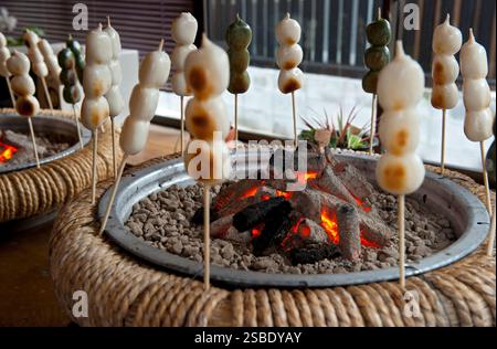 Il Dango (palline di riso mochi sugli spiedini) arrostito sopra un fuoco di carbone per una deliziosa delizia rende un popolare spuntino giapponese durante i freddi mesi invernali. Foto Stock
