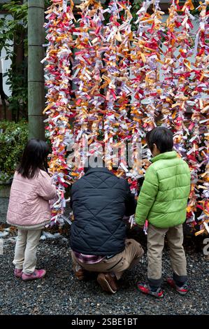 Persone che legano il loro "omikuji" (oracolo di carta di buona o cattiva fortuna) a una stringa durante "Hatsumode" (visita al santuario di Capodanno) a Taga Taisha, Hikone, Giappone. Foto Stock