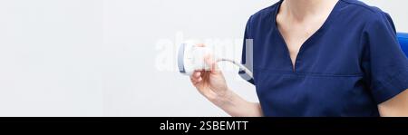 Donna medico in uniforme seduta in ufficio in un ospedale con apparecchiatura diagnostica a ultrasuoni e pronto per esaminare i pazienti e fare ultra Foto Stock