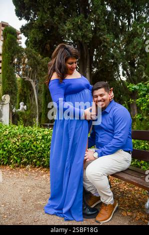 Uomo che ascolta il bambino nella pancia di una donna incinta in un parco Foto Stock