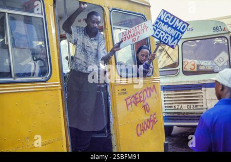 Kenia, Nairobi, un uomo e una donna stanno mostrando la direzione in cui sta andando l'autobus per attirare passeggeri. Il cartello sull'autobus indica che lo sono Foto Stock