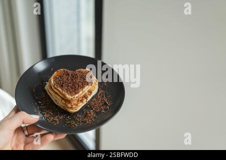 Piatto di appoggio con pancake a forma di cuore e cioccolato grattugiato Foto Stock