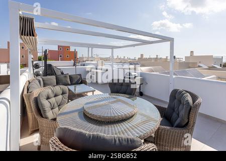 Elegante tetto a la Herrada, Montesinos, con posti a sedere in vimini, zona pranzo, barbecue, e viste panoramiche del quartiere. Foto Stock