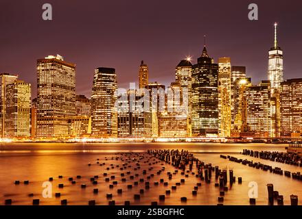 Tronchi di legno nell'East River e nello skyline di Lower Manhattan dopo il tramonto, foto a lunga esposizione di New York, vista dal Brooklyn Bridge Park Foto Stock