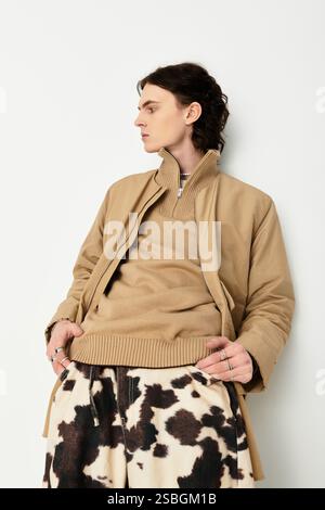 Il giovane uomo dal look alla moda mostra fiducia mentre si rilassa all'interno, dando risalto allo stile. Foto Stock