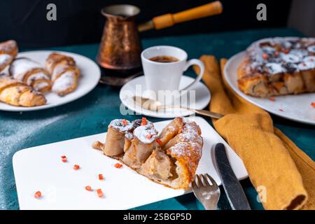 Dessert alla banana Tarte tatin e croissant su sfondo verde scuro con una tazza di caffè preparato in una cezve e lamponi liofilizzati. Alta qualità Foto Stock