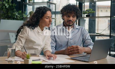 Due colleghi d'affari diversi imprenditori etnici che lavorano con il team laptop discussione uomo d'affari arabo donna d'affari ispanica piano di analisi Foto Stock