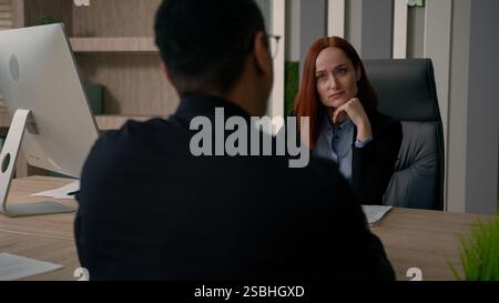 Due colleghi partner uomo d'affari afroamericano multirazziale donna d'affari caucasica parlano in ufficio trattative commerciali discutono l'avvio di un accordo Foto Stock