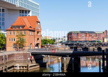 Amburgo, Germania - 12 agosto 2024: Treno regionale Nordbahn sul ponte Oberhafen con Altes Zollhaus ad Amburgo, Germania. Foto Stock