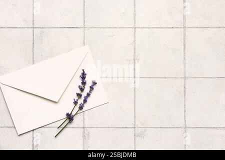 Rami di splendidi fiori di lavanda e busta su sfondo piastrellato chiaro Foto Stock